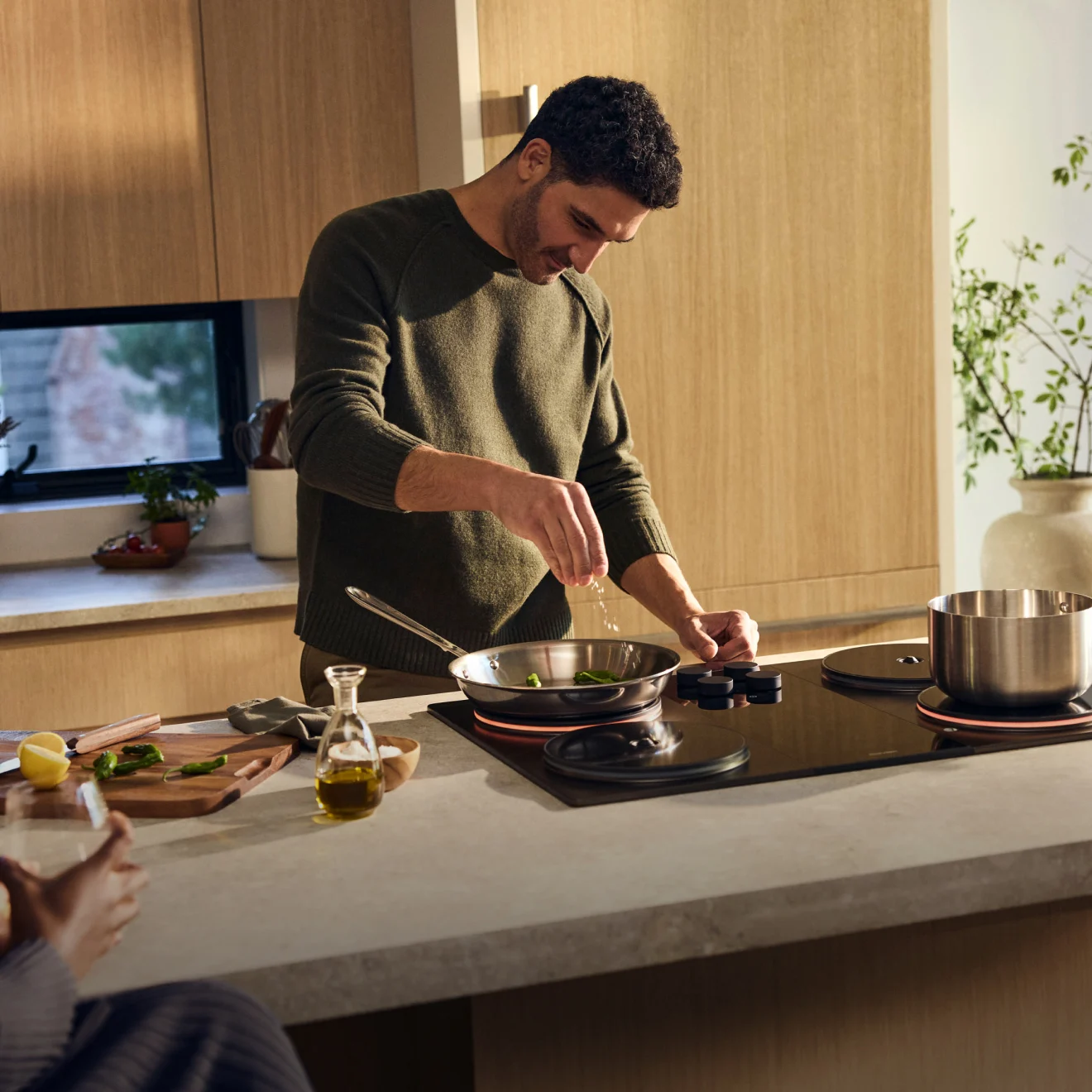 A cook seasoning a pan on the Impulse Cooktop